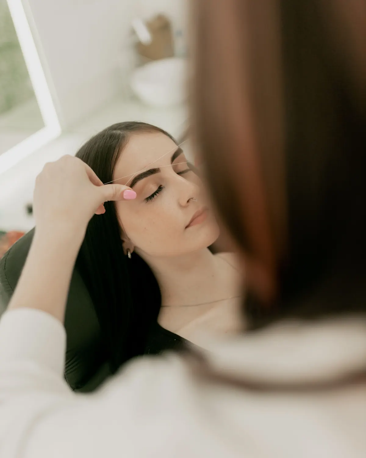 Mujer relajada durante un diseño de cejas en el salón