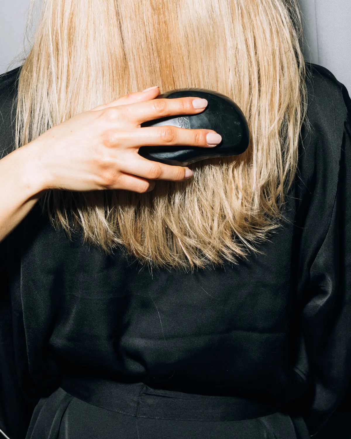 Melena rubia con mechas balayage cepillada sobre un vestido negro