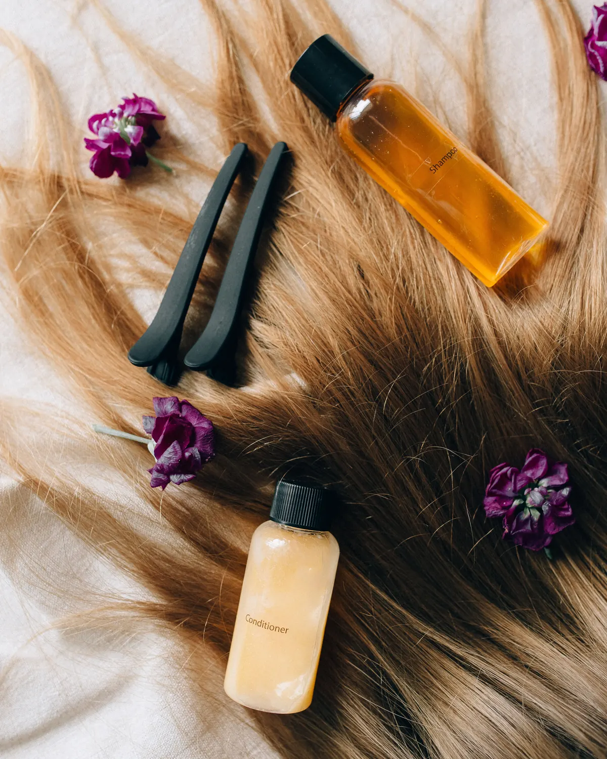 Productos de cuidado capilar y pinzas sobre una melena rubia